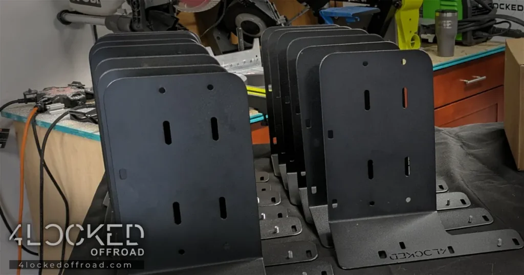 Finished powder coated 3rd Gen 4Runner ARB twin compressor mounting brackets in BK109 black lined up on workbench