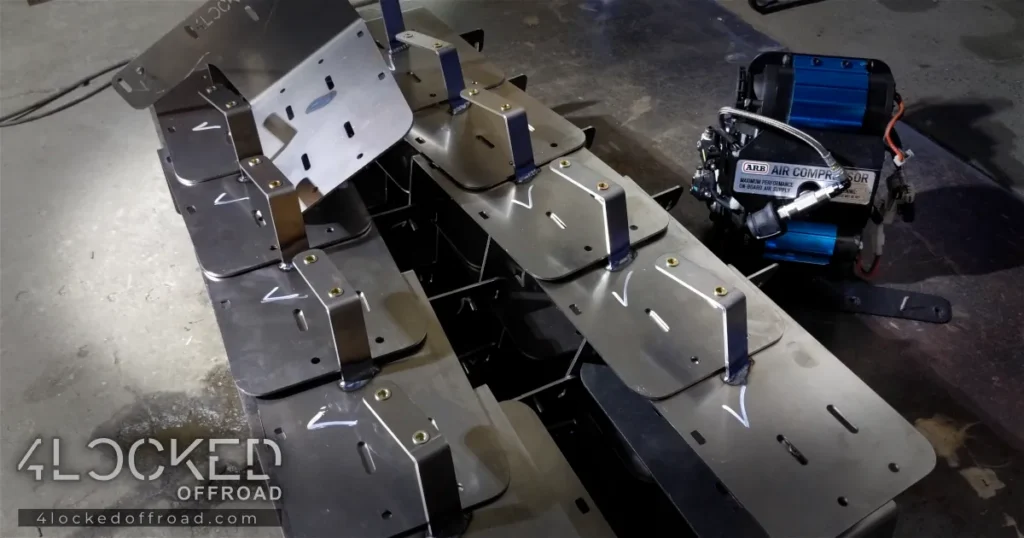 Stack of TIG welded 3rd Gen 4Runner ARB twin air compressor mounting brackets on shop table with ARB compressor mounted to finished bracket.